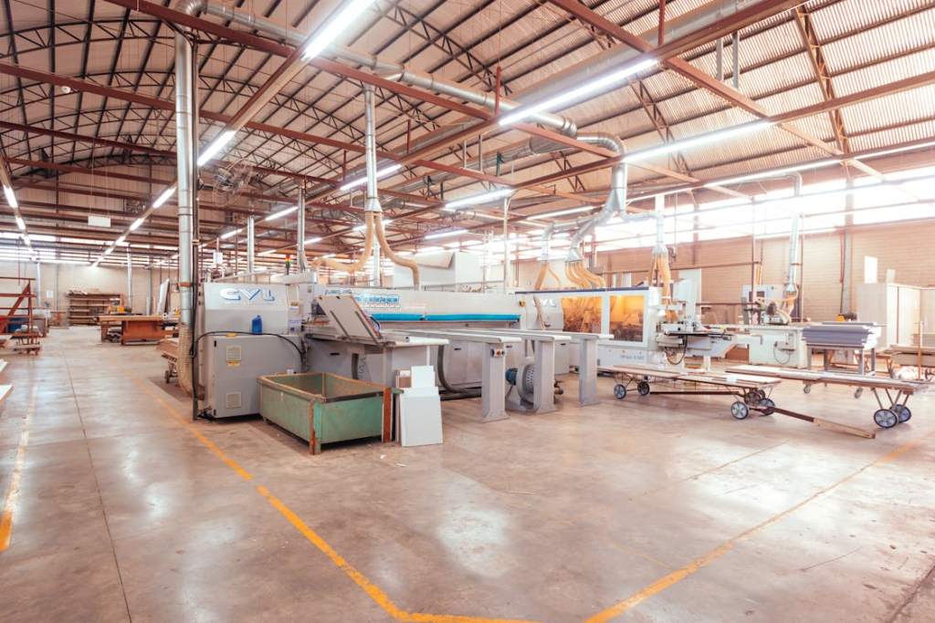 A spacious industrial warehouse featuring multiple machines, well-lit by bright explosion-proof lights for safety.