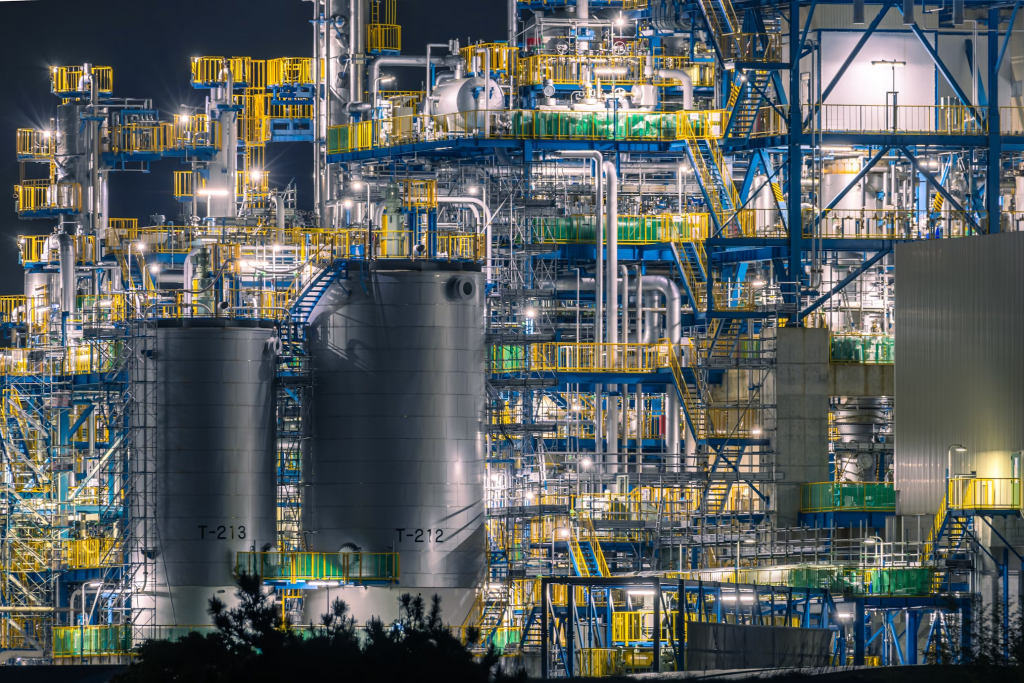 This is a brightly lit industrial plant at night, equipped with numerous explosion-proof lights ensuring safe operation in a complex environment of tanks, pipes, and metal structures.