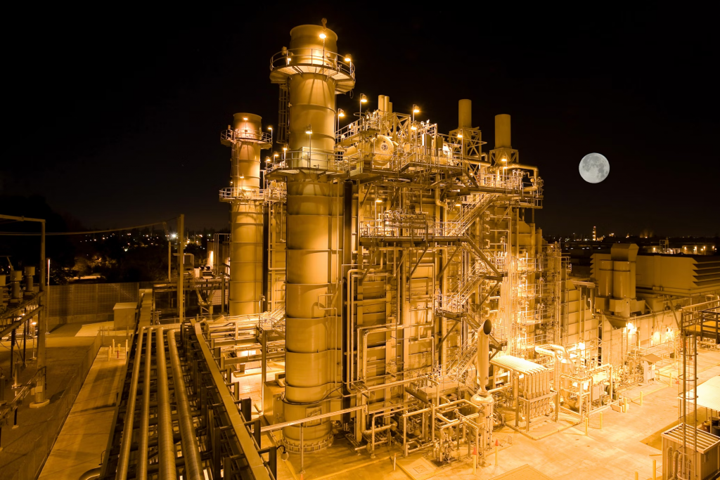 Night view of a large industrial plant with bright LED explosion-proof lights and a full moon in the sky.