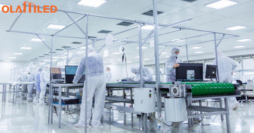 A cleanroom factory scene featuring workers in white suits, highlighted by bright, sterile lighting for safety and cleanliness.