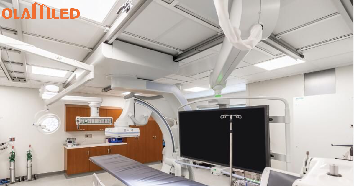 A hospital room featuring a bed, television, and medical equipment, illuminated by led cleanroom troffer lighting.