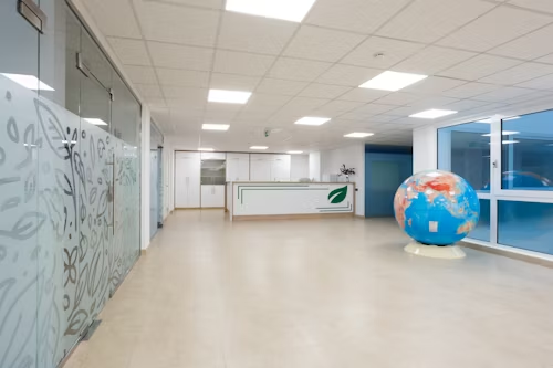 A large globe is positioned in the middle of a hallway, enhanced by the soft glow of panel lights above.