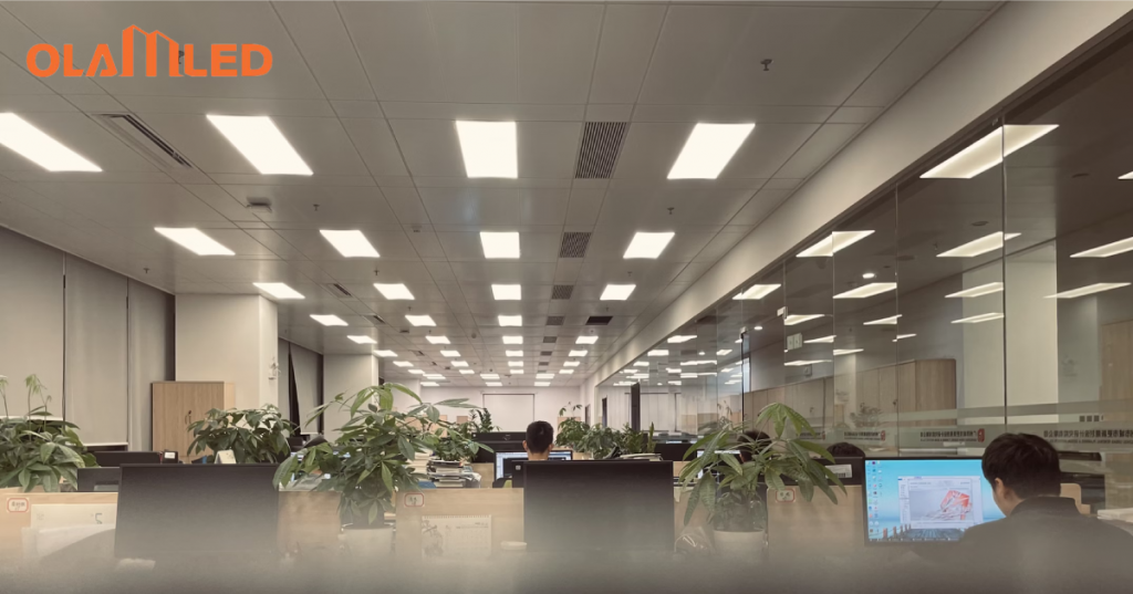 A large office space featuring employees at desks, all well lit by modern led panel lights.