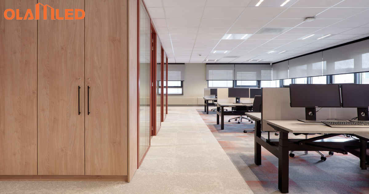 A lengthy corridor with many desks, brightly lit by energy efficient led lights.