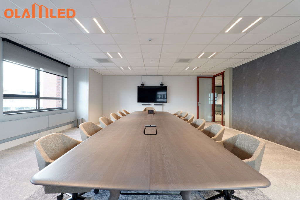 A spacious conference room with a large table and several chairs, brightly lit by overhead office lights. (2)