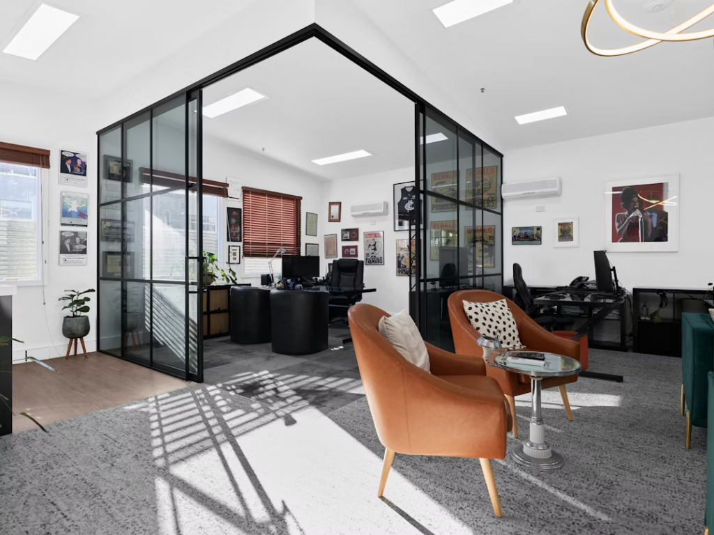 An office featuring a glass wall, modern chairs, and led lighting, creating a bright and open workspace environment.