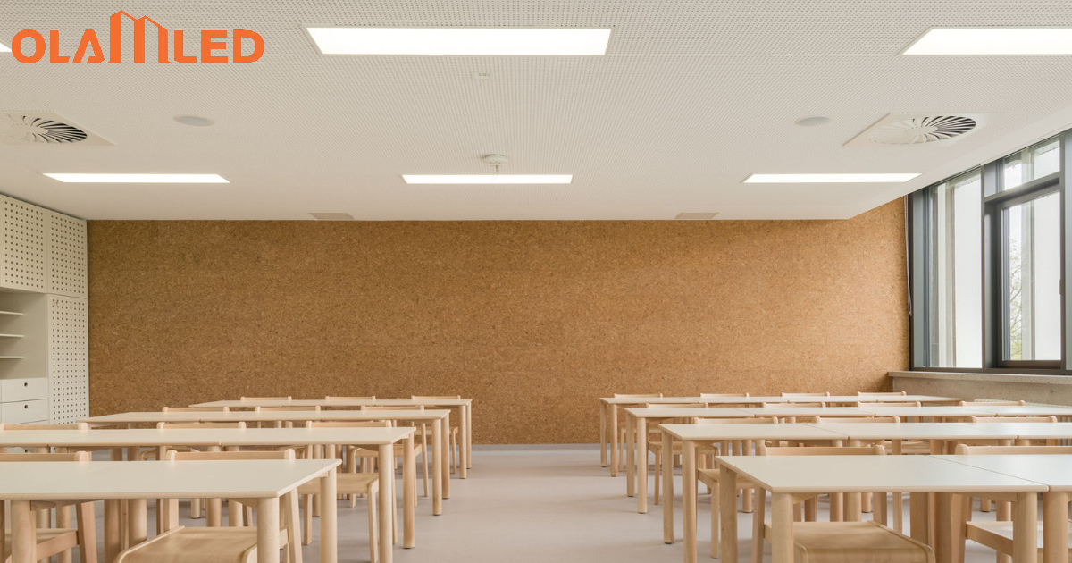 Interior of a classroom with wooden desks and chairs, brightly lit by panel lights.