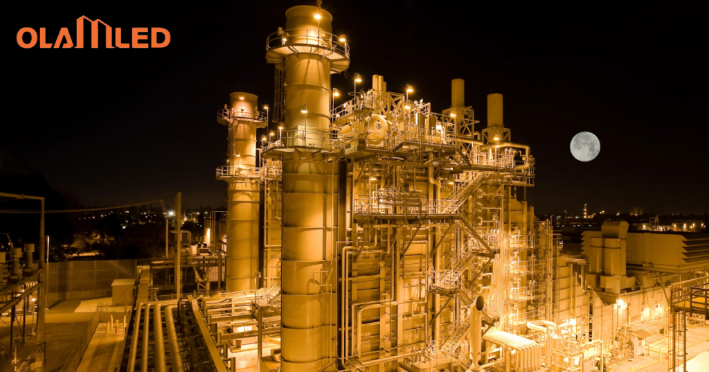 Night view of a large industrial plant with bright led explosion proof lights and a full moon in the sky.