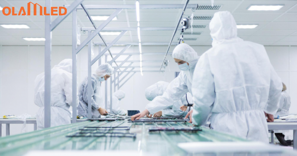 Workers in white protective suits operating a computer inside a cleanroom environment.
