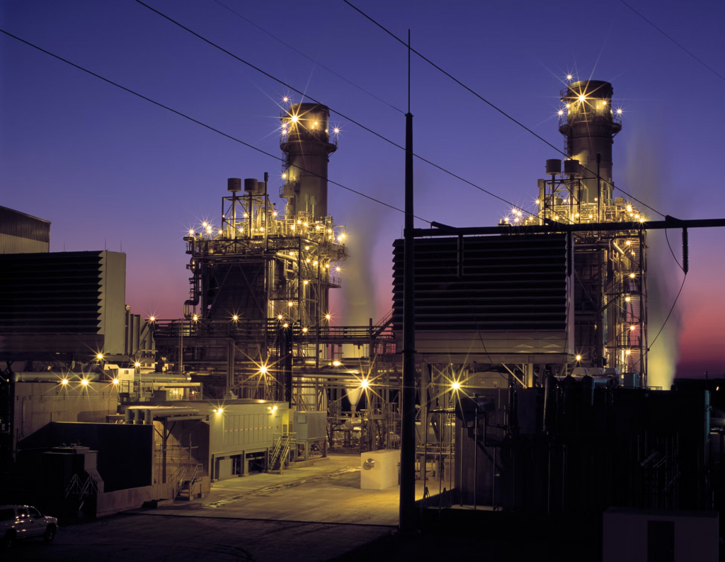A large power plant at dusk, featuring bright explosion-proof lights that enhance its structure and visibility in the evening.